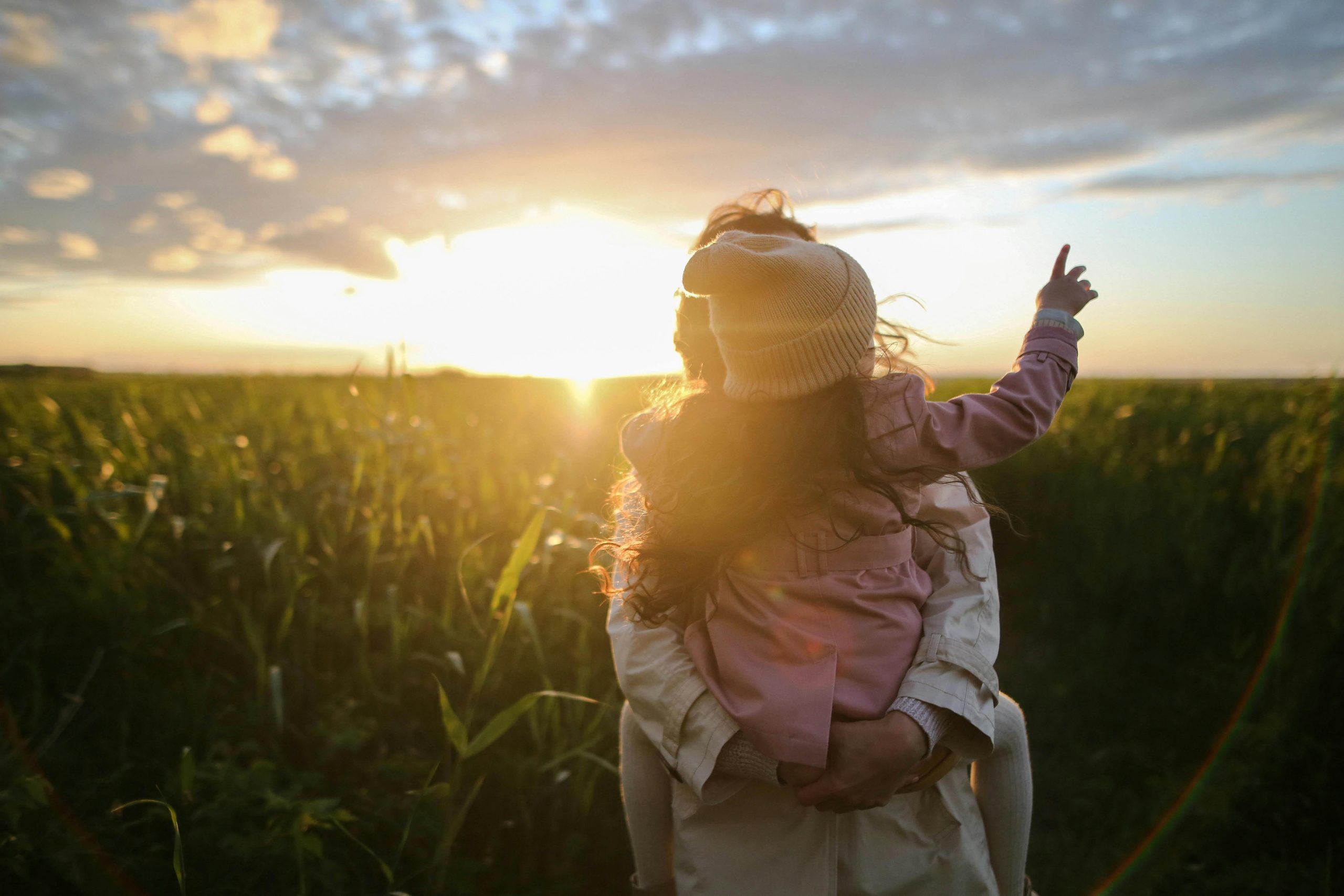 Mother holding child in field with sunset